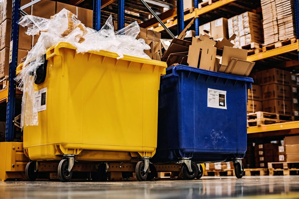 Blue and yellow large garbage bins in industrial or warehouse setting