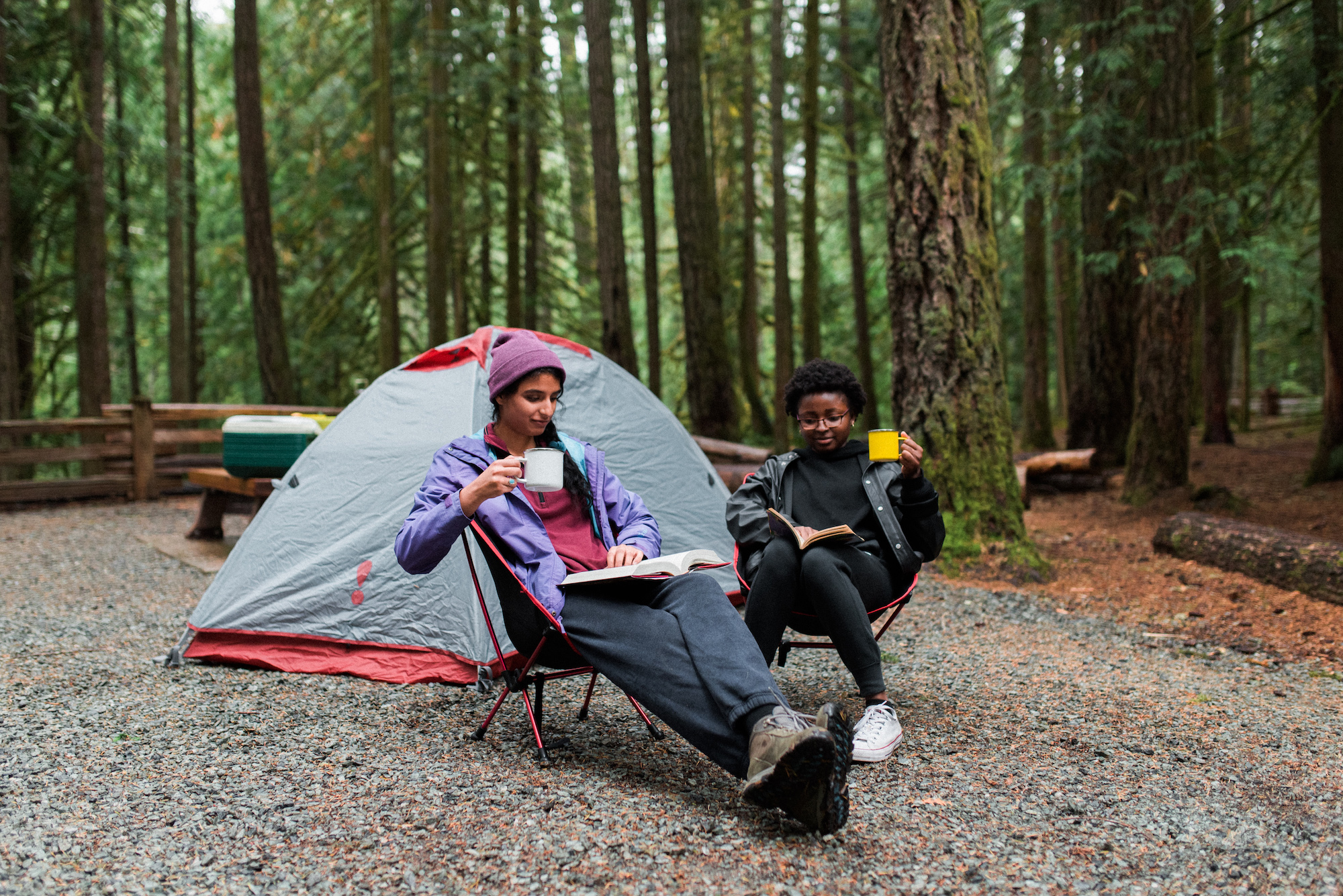 two people drinking from mugs in front of a tent on a bc parks campsite