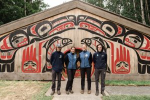 Four people standing in front of an Indigenous building.